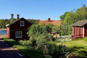 eine rote Scheune und ein Haus mit einem Zaun in der Unterkunft Kalles, skärgårdsidyll med utsikt över Hamnsundet in Saltvik