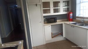a kitchen with white cabinets and a microwave at JOLLY'S PARK GUEST HOUSE in Roodepoort