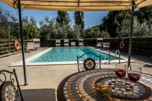 einen Pool mit einem Tisch und zwei Gläsern Wein in der Unterkunft Casale Terre del Farfa in Toffia