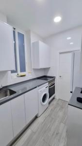 eine weiße Küche mit einer Spüle und einem Geschirrspüler in der Unterkunft Renovado apartamento en Delicias by beBalmy in Madrid