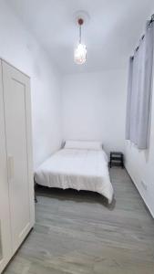 biała sypialnia z łóżkiem i żyrandolem w obiekcie Renovado apartamento en Delicias by beBalmy w Madrycie