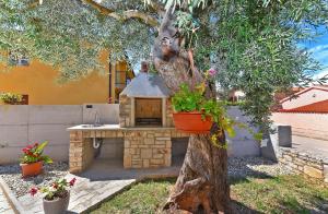 ein Baum mit einem Backsteinofen im Hof in der Unterkunft Studio für 6 Personen ca 100 qm in Fažana, Istrien Istrische Riviera in Fažana
