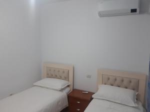 1 dormitorio con 2 camas y mesita de noche entre ellas en Emily House, en Fier