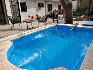 a large blue swimming pool with chairs around it at Complejo Wine Maipu: Piscina, Parrilla, Bicis in Maipú +30 photos