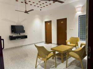 sala de estar con mesa, sillas y TV en Le Tamara Luxury en Auroville