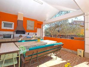 een keuken met oranje muren en een tafel en stoelen bij Ferienwohnung für 4 Personen ca 42 qm in Fažana, Istrien Istrische Riviera - b54686 in Fažana