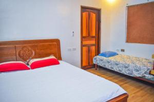 um quarto com uma cama com duas almofadas vermelhas em Casa de madera the wooden house em Cabuyao