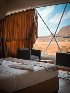 RUM NEPTUNE lUXURY CAMP في وادي رم: غرفة نوم بسرير ومنظر صحراوي