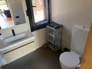 ein Badezimmer mit einem Waschbecken, einem WC und einem Spiegel in der Unterkunft Casa moderna in El Carrer de Dalt
