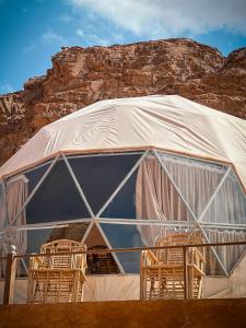 Tenda con sedie di fronte a una montagna di RUM NEPTUNE lUXURY CAMP a Wadi Rum