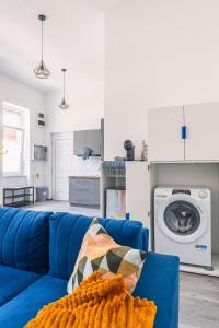 um sofá azul numa sala de estar com uma máquina de lavar roupa em Heroes' Square Stay em Budapeste