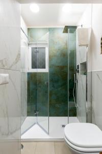 La salle de bains est pourvue d'une douche en verre et de toilettes. dans l'établissement Niloufar residence, à Naples