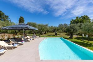 una piscina con sillas y sombrilla en olive grove studio en Áfra