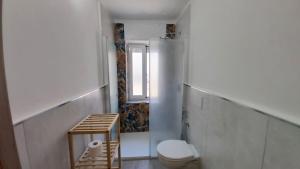 a white bathroom with a toilet and a window at Dimora Giuditta in Brindisi