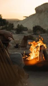 Un uomo seduto su una panchina vicino al fuoco di Moa Living a Ẕofar