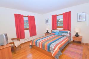 a bedroom with a bed and two windows with red curtains at Castle View - A rancher with a view! in Berkeley Springs