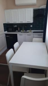 a kitchen with white cabinets and white tables and chairs at Ozef Suites in Istanbul