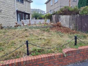 a yard with a brick wall and a fence at Hillside in Llanelli