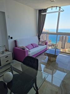 un soggiorno con divano viola e tavolo in vetro di Cielo de Benidorm a Benidorm