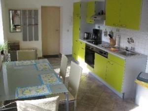 eine Küche mit gelben Schränken und einem Tisch mit Stühlen in der Unterkunft FW4 - Schönhaide in Sayda