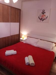 a bedroom with a red bed with two towels on it at Apartmani Vitković II Cres in Cres