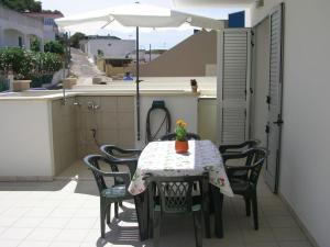 una mesa y sillas en un balcón con sombrilla en Ferienwohnung für 6 Personen ca 40 qm in Conchiglie-Alto Lido, Apulien Provinz Lecce, en Baia Di Gallipoli