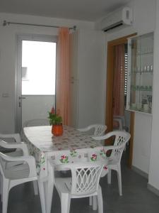mesa de comedor blanca con sillas blancas y ventana en Ferienwohnung für 6 Personen ca 40 qm in Conchiglie-Alto Lido, Apulien Provinz Lecce, en Baia Di Gallipoli