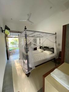 a bedroom with a bed with a mosquito net at Villa La more in Unawatuna