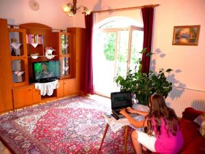uma mulher sentada numa sala de estar usando um computador portátil em Ferienwohnung für 2 Personen ca 45 qm in Hévíz, Westungarn Nationalpark Balaton-Oberland em Hévíz