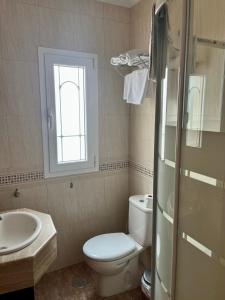 uma casa de banho com um WC, um lavatório e uma janela em PENSION NAVAS em El Cabo de Gata