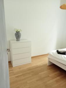 a white bedroom with a vase on top of a dresser at Stadtgrün 1 in Berlin