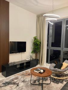 ein Wohnzimmer mit Fernseher und Tisch in der Unterkunft SINA Troika Residence Kota Bharu 1BR Netflix Pool in Kota Bharu
