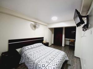 a bedroom with a bed with a black and white comforter at Hotel Perú Pacífico in Lima