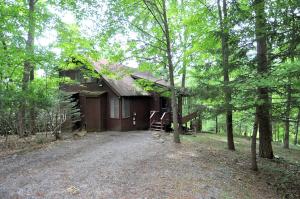 a cabin in the woods with a gravel driveway at Treetop Cabin in Hedgesville