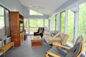 a living room with a couch and chairs and a tv at Treetop Cabin in Hedgesville