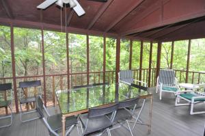 a screened in porch with a glass table and chairs at Treetop Cabin in Hedgesville