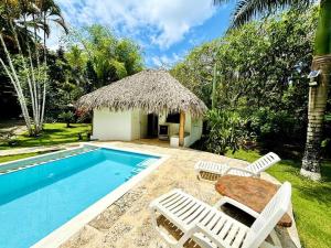 a pool with chairs and a table and a hut at Zen Garden Poolside Bungalow in Las Terrenas