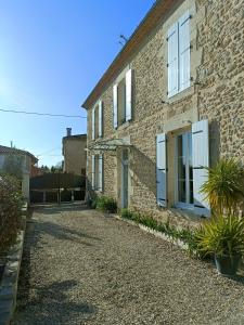 a brick house with white windows and a gravel driveway at L'atelier Détente et Spa in Caudrot