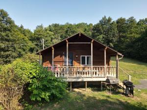 a log cabin with a deck and a grill at Whispering Hills - Couples Getaway in Hedgesville