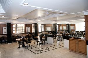 a restaurant with tables and chairs in a room at Suvarna Residency in Mysore