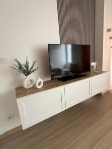 a white entertainment center with a flat screen tv on it at La petite M in Tréméreuc +2 photos