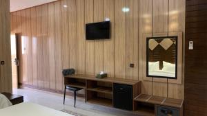 een kamer met een bureau en een televisie aan de muur bij Hotel Oasis Palace in Er Rachidia