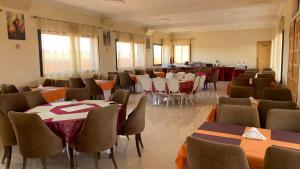 uma sala de jantar com mesas e cadeiras e mesa de cabeceira em Hotel Oasis Palace em Errachidia