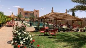 un complejo con mesa, sillas y piscina en Hotel Oasis Palace, en Er Rachidia
