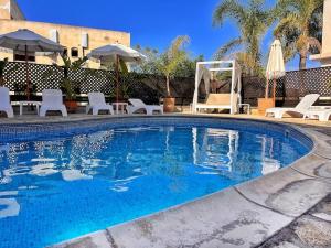 a large swimming pool with white chairs and umbrellas at TEO Apartment in Paphos