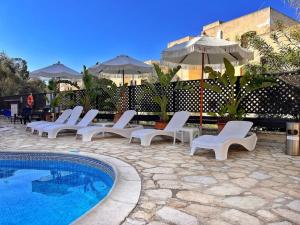 a group of white chairs and an umbrella next to a pool at TEO Apartment in Paphos