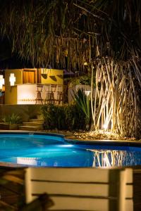 dwa baseny w ośrodku z oświetleniem w obiekcie Pousada Coisa e Tao w mieście Arraial d'Ajuda