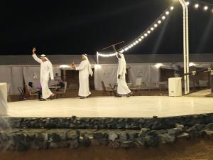 Eine Gruppe von Personen, die auf einer Bühne auftreten in der Unterkunft Margham Desert Safari Camp in Margham
