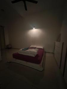 un piccolo letto in una stanza con una luce sul muro di DAHLIA Homestay a Jitra