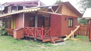 une petite maison rouge avec une terrasse couverte dans la cour dans l'établissement Cabañas Buen Recuerdo, à Puyehue